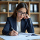 Jeune femme en bureau lisant un rapport annoté avec concentration